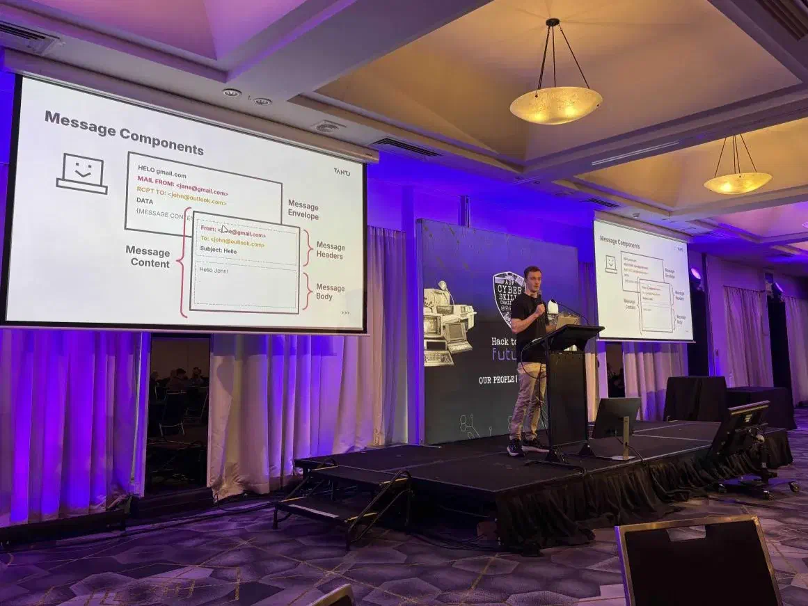 Ben Wilson presenting at the ADF Cyber Skills Challenge, beside a slide on an emailâs message components: envelope, headers and body