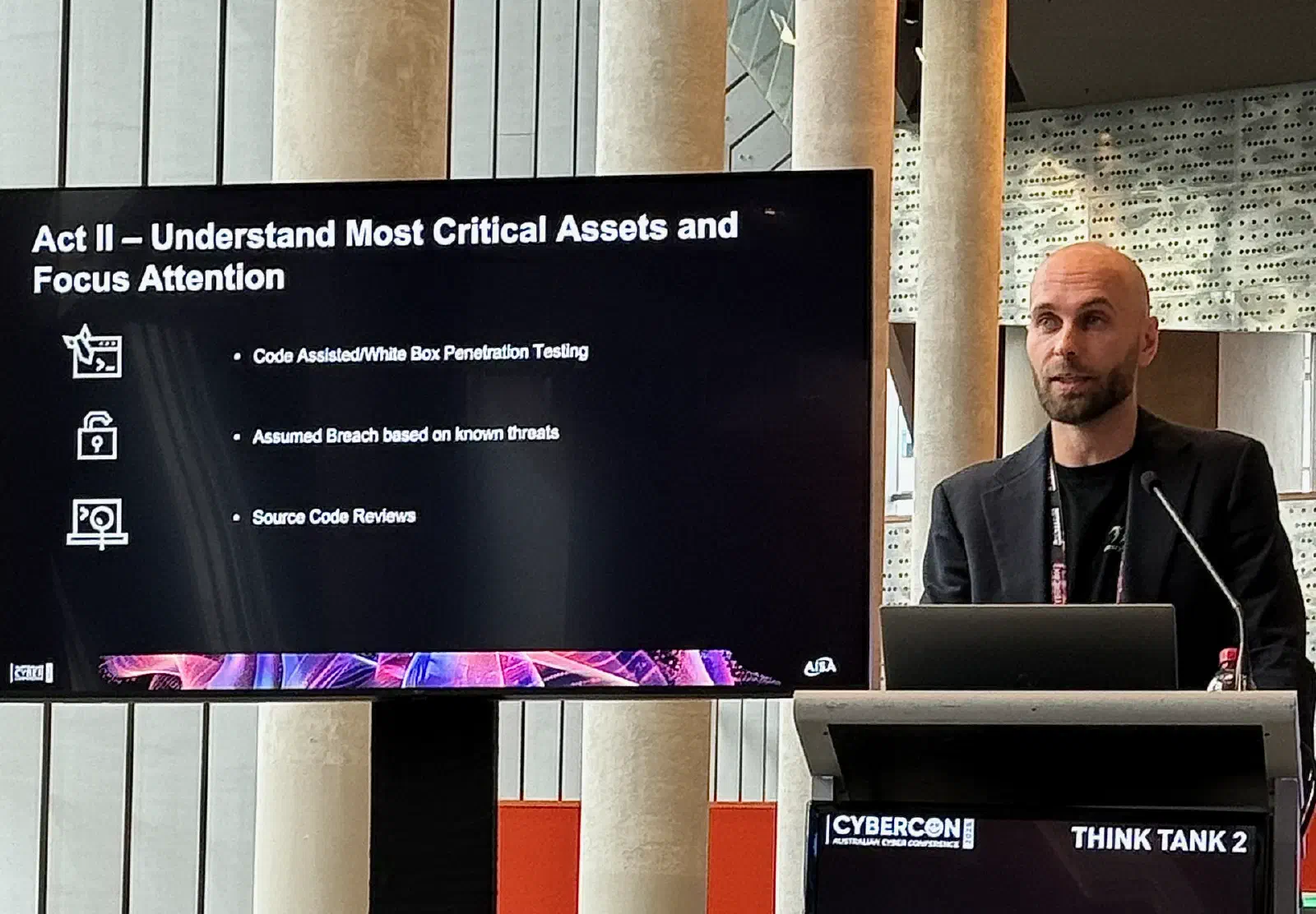 Marco presenting at a lectern in CyberConâs Think Tank 2, beside a slide, âAct II â Understand Most Critical Assets and Focus Attentionâ