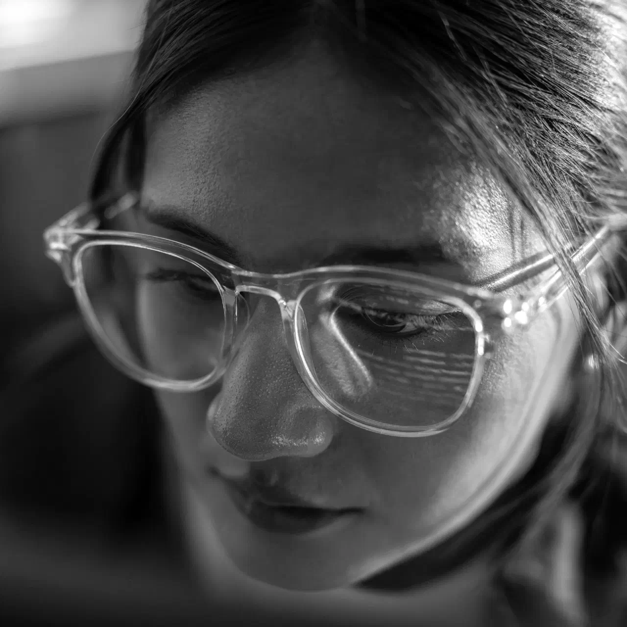 A person in glasses reading a screen, its code reflected in the lenses.
