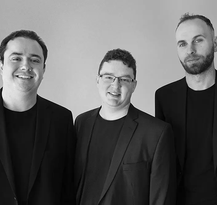 A welcoming grayscale shoulder shot of Tanto Security's founders smiling in business attire.