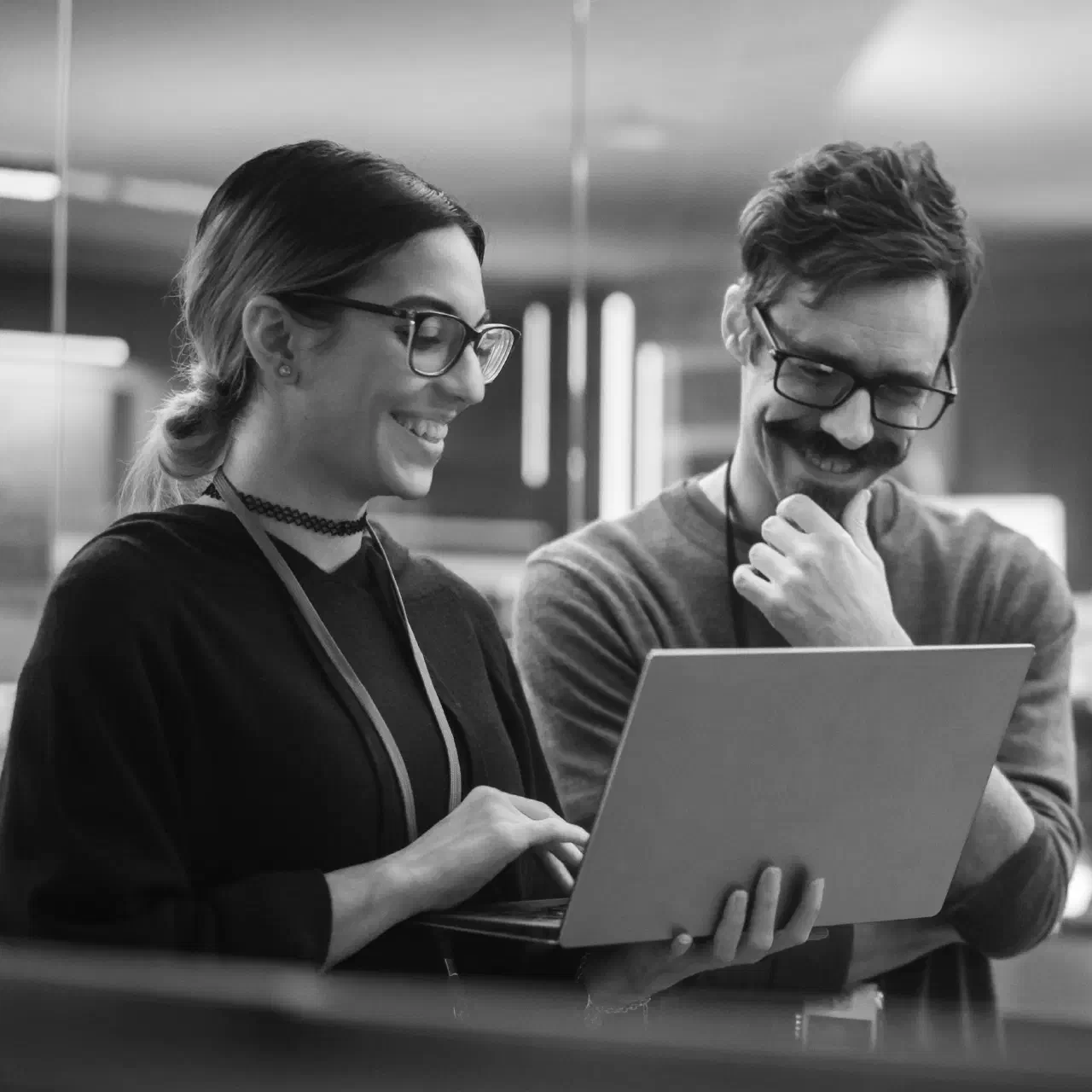 Two people smiling over a laptop.